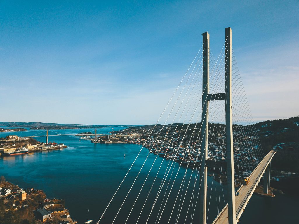 A striking aerial view of a modern suspension bridge crossing a wide river under clear skies.