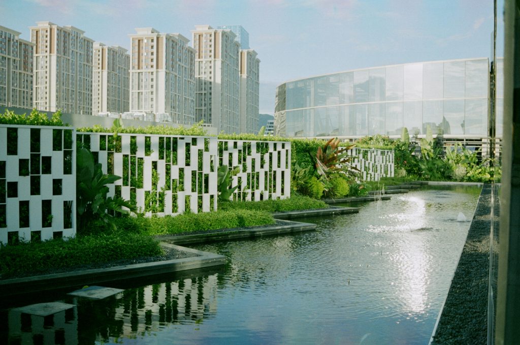 Contemporary urban building landscape with a reflecting pool and greenery.